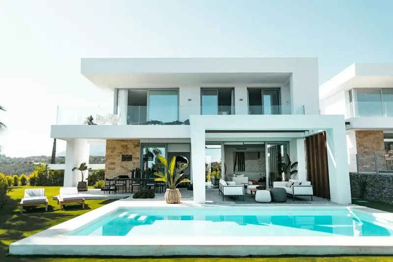 Casa blanca de dos plantas con piscina y jardín
